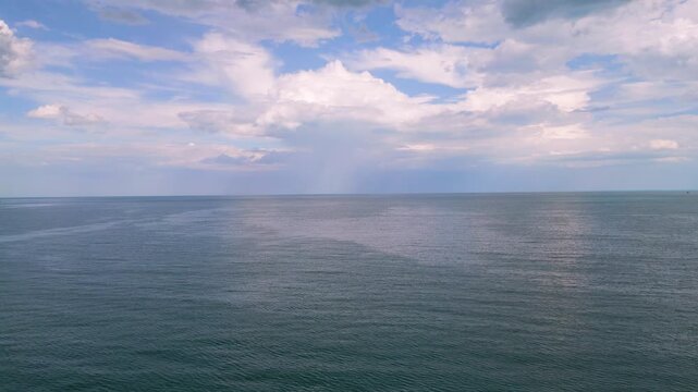 Scenic view of calm blue ocean under dramatic sky with fluffy clouds