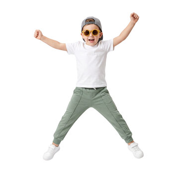 Joyful boy jumping with arms raised, wearing sunglasses and baseball cap