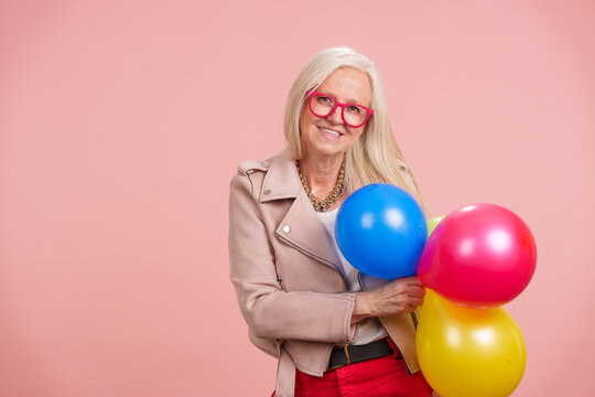Senior woman celebrating lively aging holding balloons