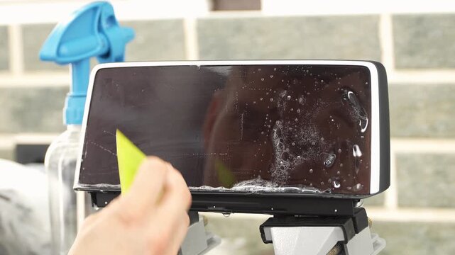 A man wrapping a protective PPF film on a car monitor. The protective glass or film protects the monitor from scratches, fingerprints and other mechanical damage. Wrapping a protective film. 