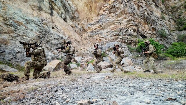 Elite soldiers advance through a combat training scenario with simulated explosions during an intensive military field exercise