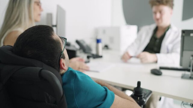 Man with a physical disability sitting in an electric wheelchair during a consultation with his doctor. Patient with spina bifida talking at the clinic