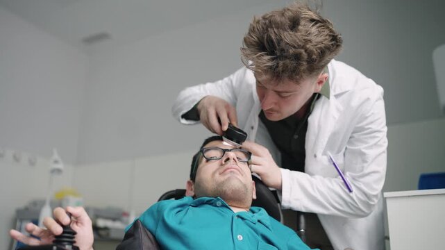 Professional dermatologist conducting a skin examination on a male patient with spina bifida sitting in an electric wheelchair