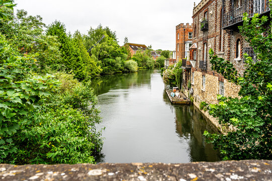 The River Thames (locally called the Isis) seen from Folly Bridge, with lush riverside vegetation and punts and houseboats moored along the bank, in Oxford, England, UK