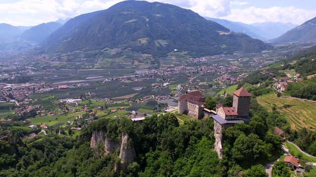 Castel Tirolo South Tyrol Italy 4K Drone. Aerial overflight from above medieval castle with green vineyard terraces and mountain valley view. Impressive alpine fortress b roll cinematic video