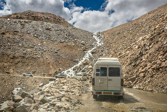 Vehicles crossing a water ford on a mountain dirt road in Ladakh
