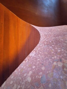 Abstract architectural background featuring a curved terrazzo stone surface intersecting a warm wooden wall texture, ideal for B2B copy space.