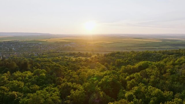 Madara plateau valley panoramic drone view sunset golden hour orange sun light green forest trees rural village plain fields summer travel destination Shumen region Bulgaria landscape background.