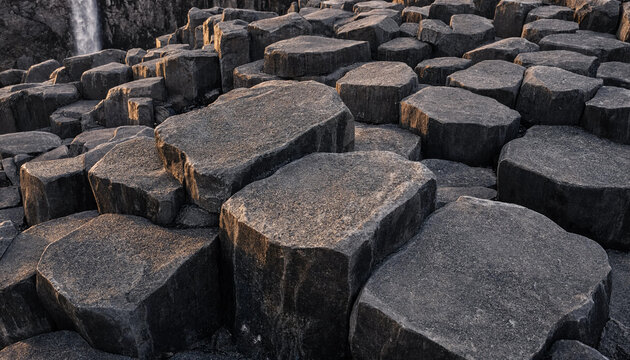 Close-up of dark basalt rock columns with hexagonal geometric patterns and rough stone textures found in a natural volcanic landscape