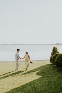 Couple walking hand in hand by the serene lakeside at sunset