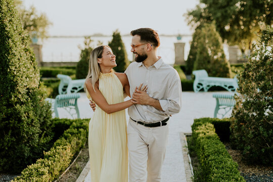Couple enjoying a romantic stroll in a beautifully landscaped garden at sunset