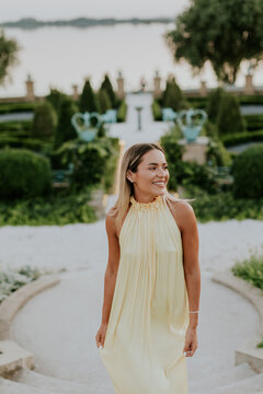 Young woman walks down steps in garden during evening near water in summer