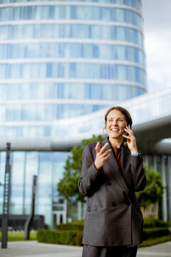 Business person talks on phone outside modern office building in urban area