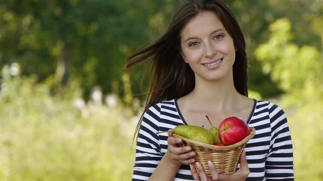 woman holding a basket of fruits and eating apple