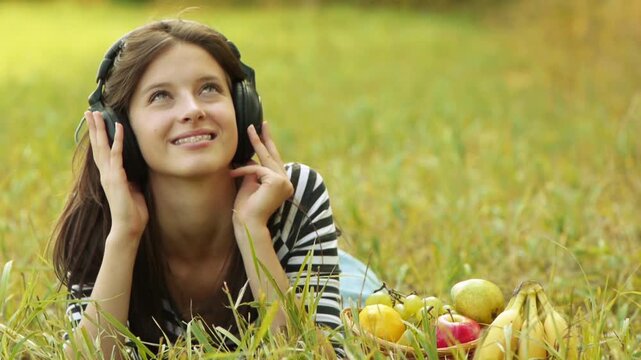 young woman lying grass headphones fruit