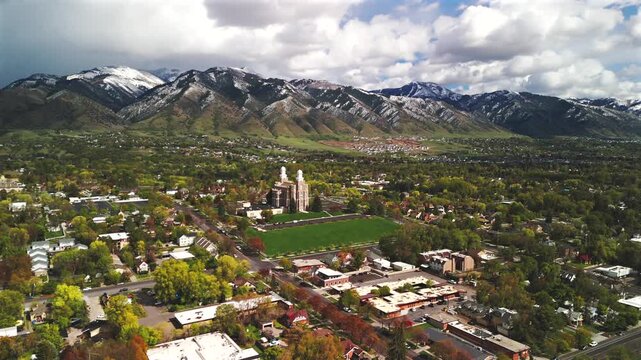Drone orbits clockwise around a hilltop landmark surrounded by lawns, trees and dramatic clouds