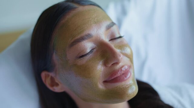 Extreme closeup of young womans face with golden mud mask, 4K footage