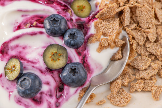 Creamy yogurt bowl with swirl of berry compote, fresh blueberries and crunchy cereal