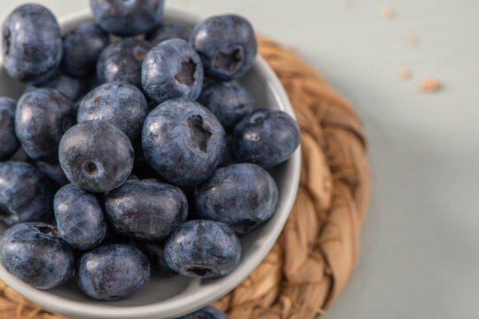 Fresh ripe blueberries in a ceramic bowl on a woven placemat