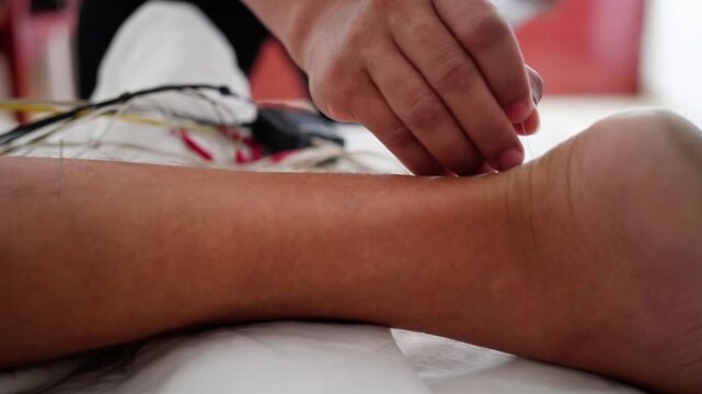 legs being massaged in a relaxed medical or therapeutic setting with electrodes and cloth visible in a close-up side view period period period period period period period period period.