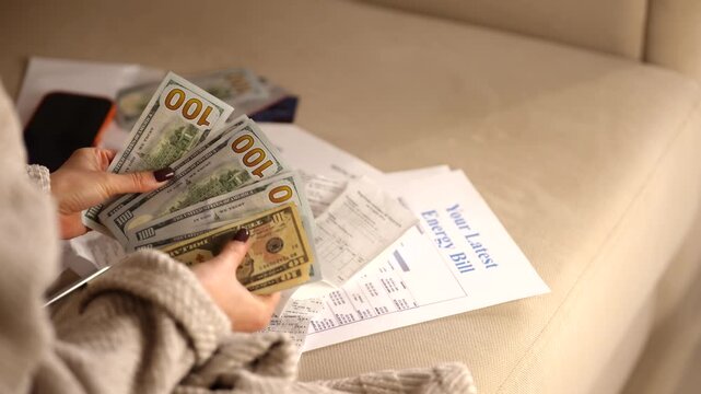 Homeowner Counting US Dollar Cash Banknotes For Paying Utility Electricity Bill. Energy Costs Document
