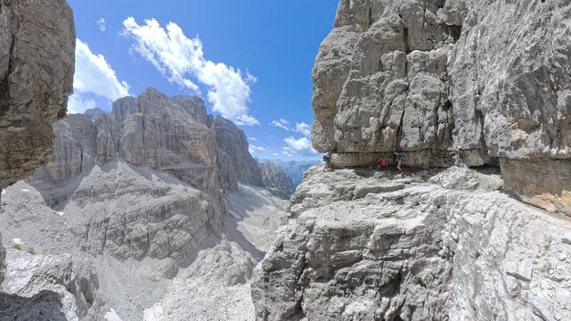 Group of hikers traversing a narrow ledge on Via Ferrata Bocchette Centrali above Brenta Valley