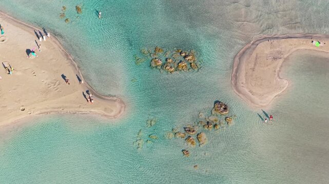Overhead aerial drone view of sandbars and clear shallow turquoise water with people walking, Elafonissi, Greece
