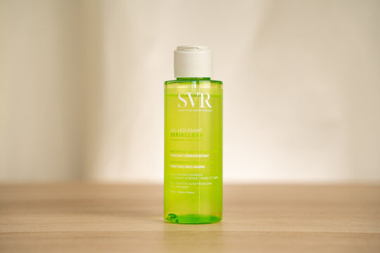 STRASBOURG, FRANCE - JULY 2, 2026 : Bright green SVR gel cleanser bottle photographed on a wooden table with soft neutral background, suitable for beauty product, skincare, and cosmetic packaging uses