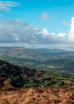 A wide-angle landscape photograph capturing the scenic, rolling green valleys and distant peaks of the Black Mountains in Wales, showcasing the region's rural beauty, diverse topography, and natural.