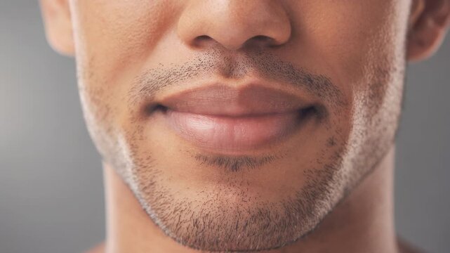 Close up video of young man lips and subtle stubble highlighting natural skin texture and facial features
