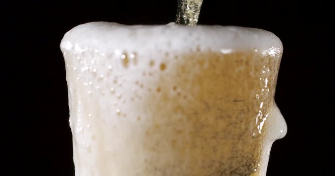 Pouring beer into a glass with rising foam in super slow motion
