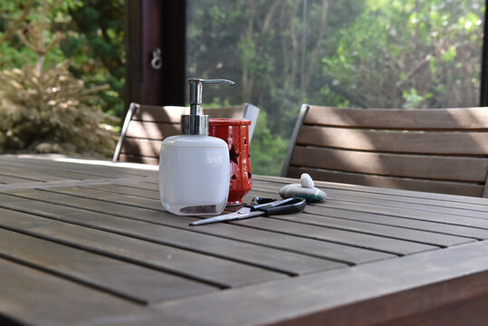 Soap dispenser and red tea light holder on a slatted wooden table