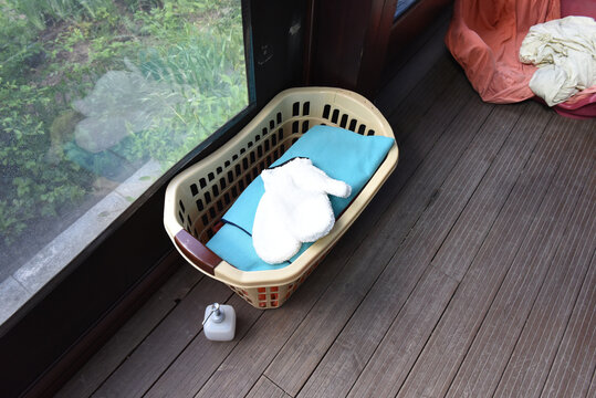 Laundry basket with folded towels and soap dispenser on a wooden deck