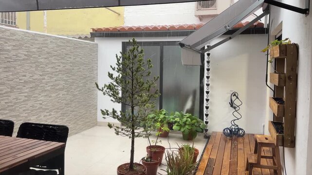 Heavy rainfall and strong wind during a summer downpour storm in a modern backyard with a wooden deck