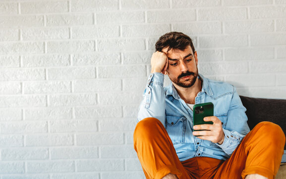 Tired, frustrated man staring at his phone, digital overload, mental fatigue, technology frustration