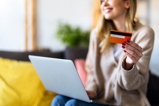 Smiling woman working on an e-commerce business at home using laptop and credit card
