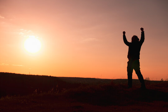 Jubilant Silhouette Celebrating with Arms Raised at Sunset