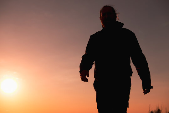 Close-Up Silhouette Walking Into Frame with Sunburst on the Left