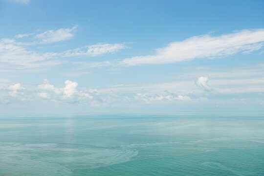 calm turquoise black sea beneath blue sky and layered white clouds, an airy natural background for hydration, breathing exercises, heat relief, mindful travel and summer wellness
