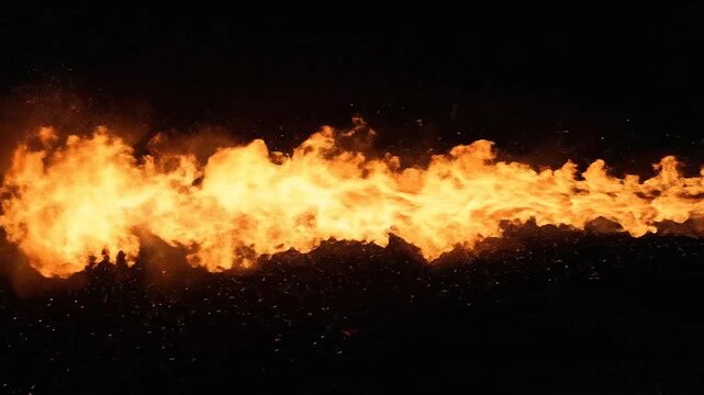 A powerful stream of bright orange flames erupts against a dark background