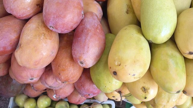 Close-up of fresh red and yellow mangoes piled at a local market stall. Symbolizes tropical agriculture, healthy eating, and summer harvest. Ideal for raw superfood, healthy diets, and health concept