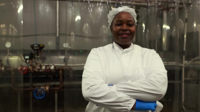 Female production supervisor wearing white uniform (PPE) stands arms crossed meticulously overseeing the production line canned mackerel loaded conveyor belt industrial seafood processing plant.