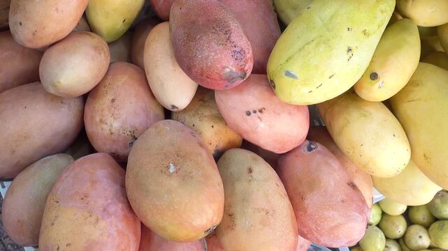 Close-up of fresh red and yellow mangoes piled at a local market stall. Symbolizes tropical agriculture, healthy eating, and summer harvest. Ideal for raw superfood, healthy diets, and health concept