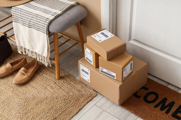 Plakat Stack of cardboard delivery boxes on a welcome mat at a residential front door, online shopping and shipping concept, Multiple packages with shipping labels are ready for pickup or recently