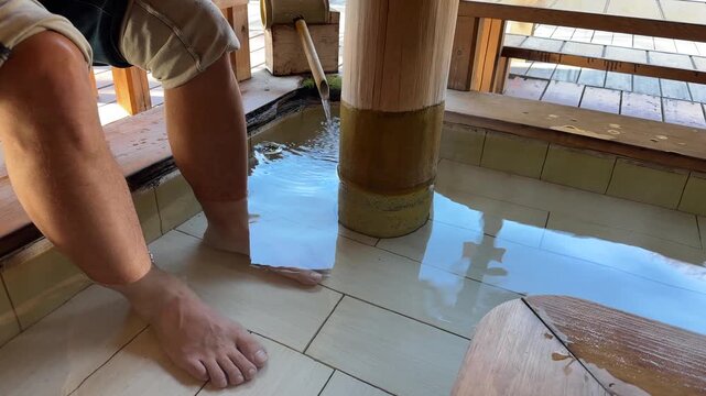 Person soaking feet in a traditional Japanese ashiyu, a public hot spring foot bath