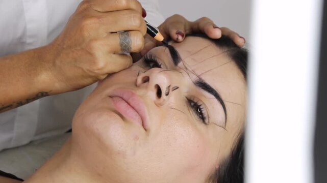 A professional woman is shaping a customer's eyebrows with a specialized pencil inside a beauty salon in Neiva, Huila, Colombia. Concept of handmade and personal care