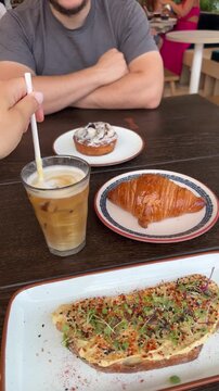 Delicious breakfast with toast, croissant, and iced coffee on a wooden table