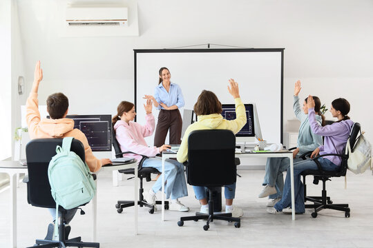 Teenage students with teacher studying at school computer lab