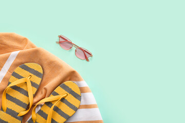 Obraz premium Flip-flops, beach towel and sunglasses on turquoise background, closeup