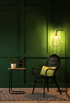 Interior of dark room with glowing lamps, chair and table at night